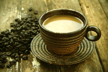 Coffee in a glass made of wood with coffee beans on a wooden floor.
