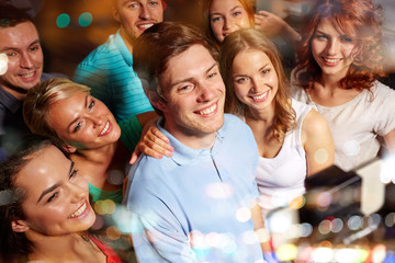 friends with smartphone taking selfie in club