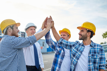 close up of builders in hardhats making high five