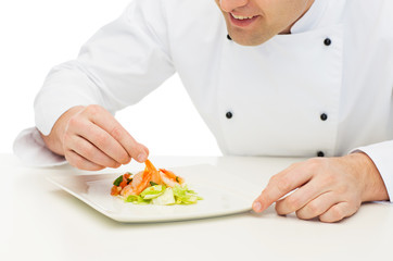 close up of happy male chef cook decorating dish