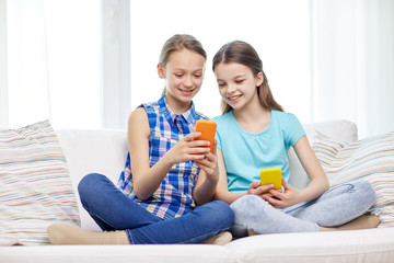 happy girls with smartphones sitting on sofa