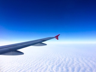 Fototapeta premium Wing of the plane with cloudy sky on background