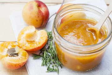 Homemade apricot jam and fresh apricots with leaves on the wooden table