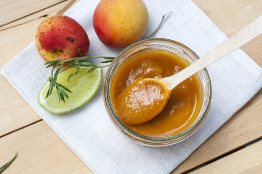 Homemade apricot jam and fresh apricots, lime and  rosemary with leaves on the wooden table