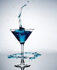 Blue cocktail with splash on white background 