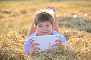 Boy teenager playing on a tablet in the field