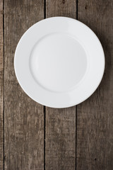 Empty plate on old wooden background. Top view
