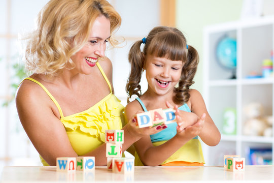 Mother and her kids play with cubes making the word dad