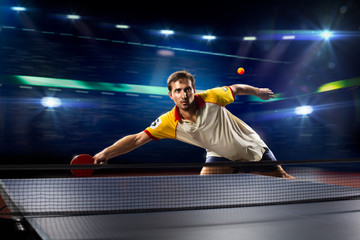 young sports man tennis player playing on black background with