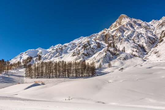 Winter landscape in Samnaun, Switzerland. Snowy mountain, forest and ski slope.