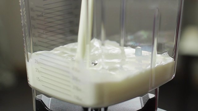 Milk is poured into a blender. Preparation of milkshake.