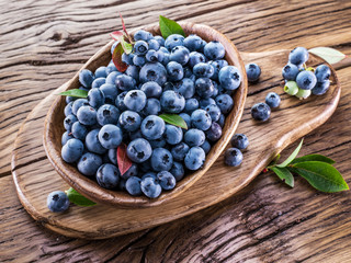 Ripe blueberries in the bowl on the wooden table.