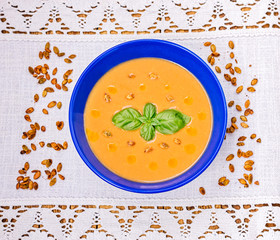 Red lentil cream soup with spiced roasted pumpkin seeds, olive oil and basil leaves garnish