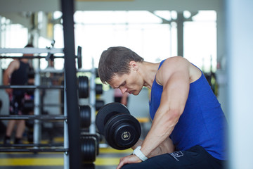 Fototapeta na wymiar Man bodybuilder execute exercise with dumbbells in gym. 