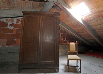 Fototapeta na wymiar wooden wardrobe and an antique chair in the dusty attic