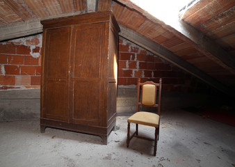 wooden wardrobe and an antique chair in the dusty attic