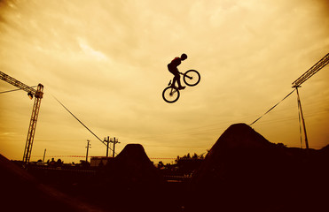 Silhouette of a man doing a jump with a bmx bike against sunset