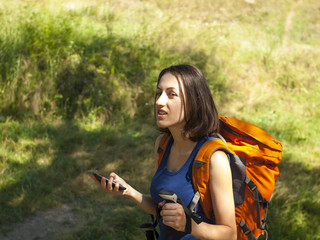 A young girl with a backpack use the phone.