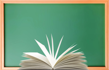 Green school blackboard and openned book