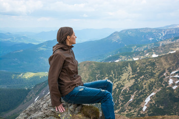 Naklejka premium Girl is sitting on a mountain top