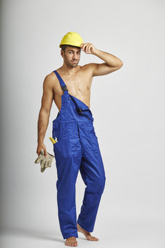 Halbnackter Handwerker mit Helm h&auml;lt seine Handschue in der Hand