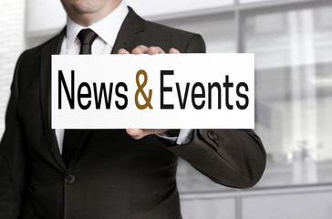 News and events sign is held by businessman