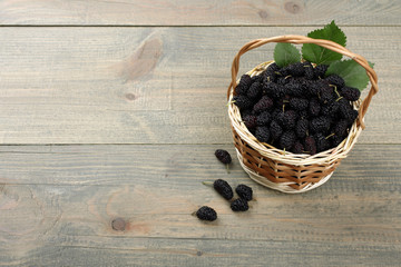 wood background, mulberry in wicker basket