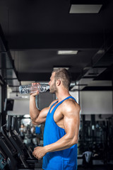 Fototapeta na wymiar Young man drinking water in gym