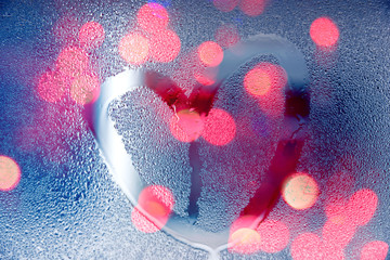 Rain at night, draw heart shape on wet glass with light