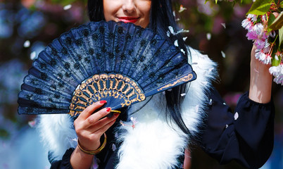 Smiling young woman and flower with ornamental fan and wolf fur