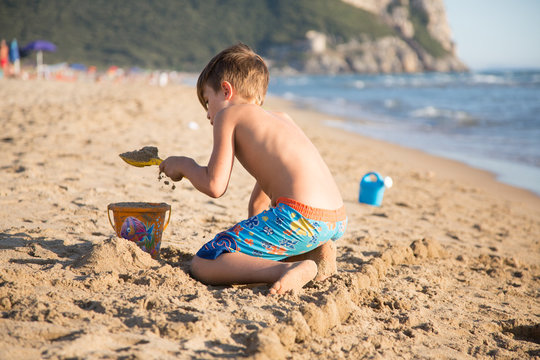 Bambino biondo di spalle che gioca sulla spiaggia