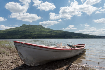 Naklejka na ściany i meble lonely fishing boat on lake with cloudy sky