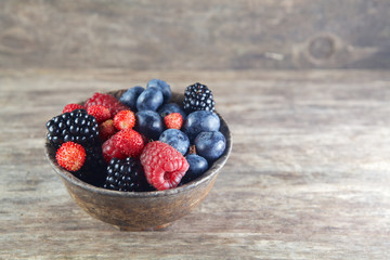 Assorted berries in bowl on wood