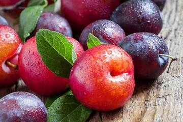 Ripe blue and red plums on old wooden background, selective focu