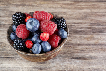 Assorted berries in bowl on wood