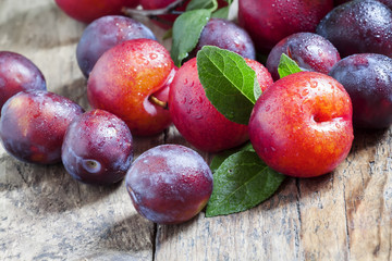 Ripe blue and red plums on old wooden background, selective focu