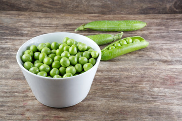 Green peas in wooden bowl on wood