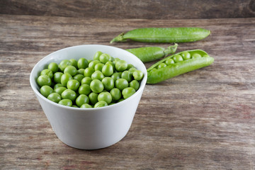 Green peas in wooden bowl on wood