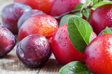 Ripe blue and red plums on old wooden background, selective focu