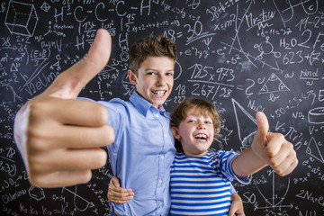 Cute little boy and girl in front of a big blackboard.