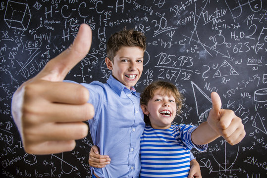 Cute little boy and girl in front of a big blackboard.