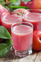 Delicious fresh juice of red and blue sweet plums and peach in a