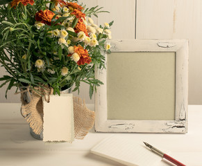 Retro photo frame and old pen with sheet paper and tagetes bouquet
