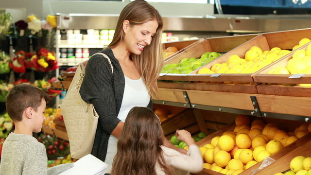 Mother and children picking out fruit in supermarket