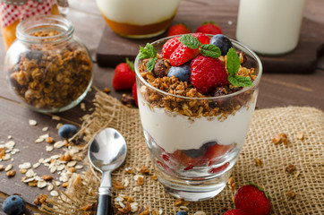 Yogurt with baked granola and berries in small glass