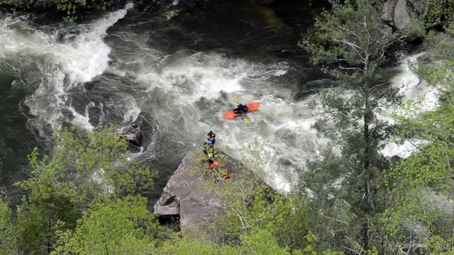 A kayaker runs a rapid in front of a photographer capturing the run