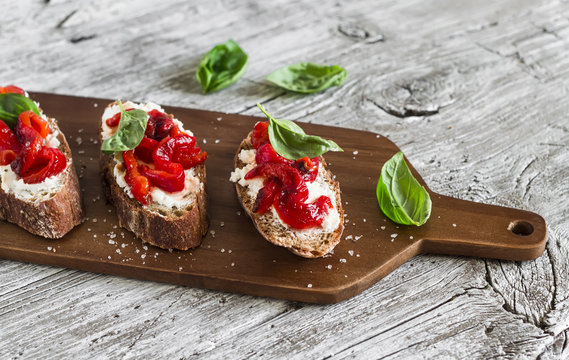 bruschetta - rye baguette, feta cheese, roasted peppers and Basil on a light wooden surface