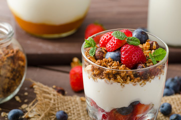 Yogurt with baked granola and berries in small glass