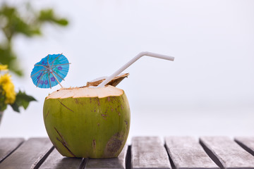 Coconut water drink served in coconut with drinking straw on the table - obrazy, fototapety, plakaty