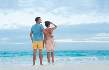 Back view of couple in bright clothes having fun at tropical